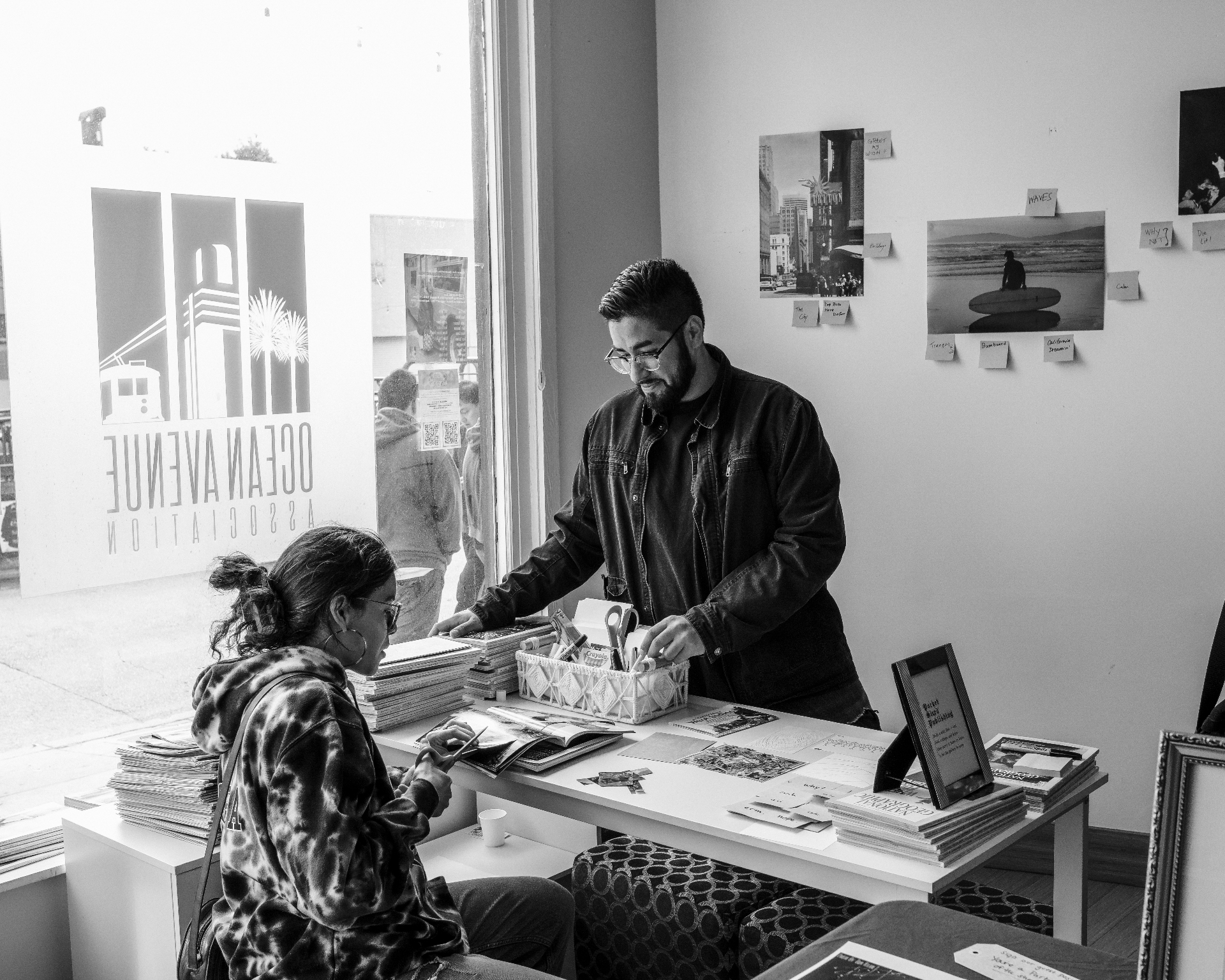 Two people browsing photographs and printed materials at a First Door Collective event